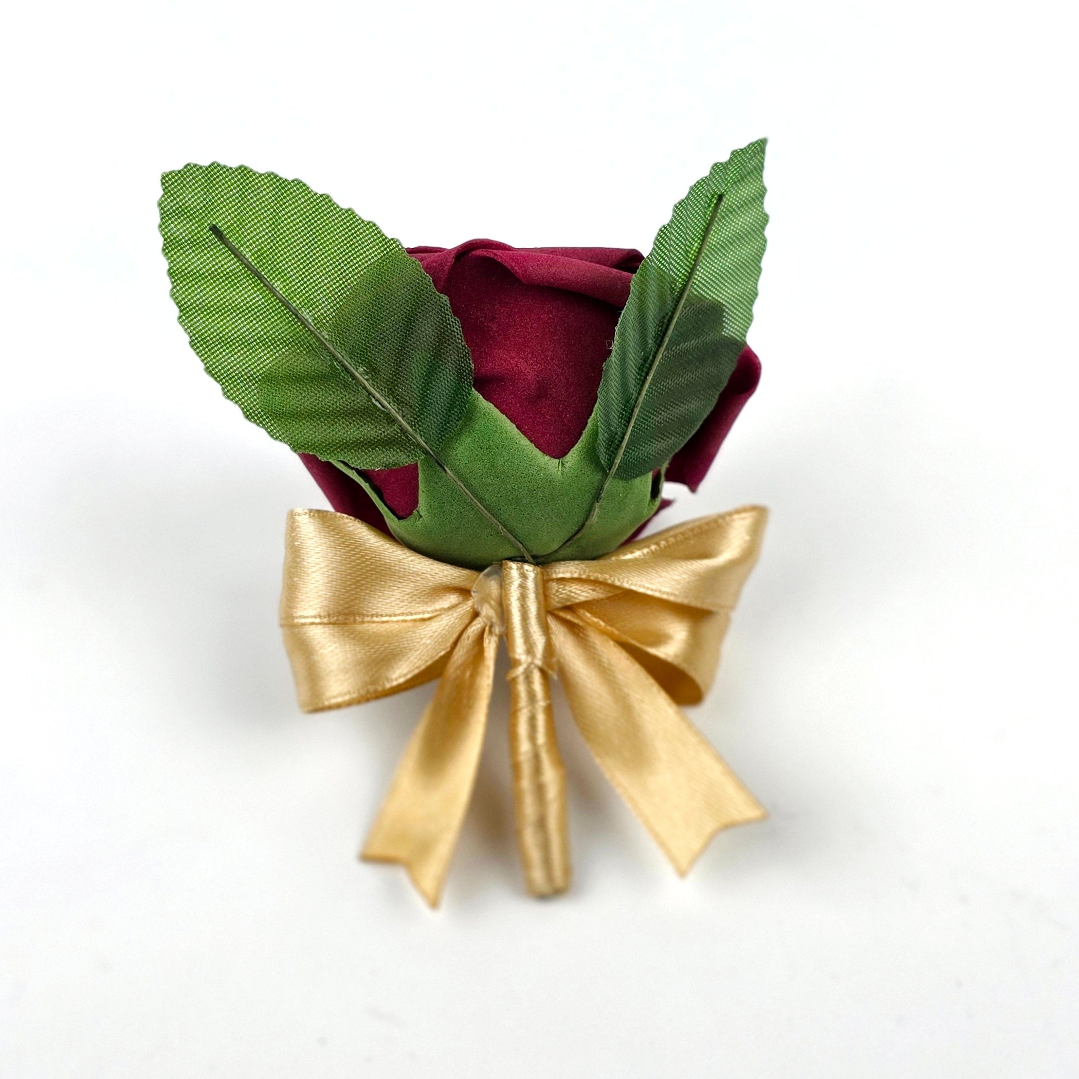 The back of a burgundy rose boutonniere with gold ribbon and 2 leaves