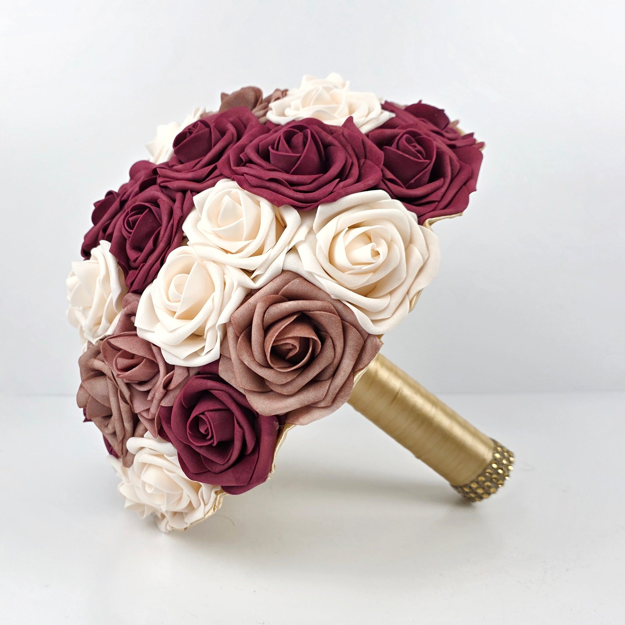 Burgundy, cream, and dusty rose 10 inch bridal bouquet with gold ribbon. Handle has a gold brooch and gold bling wrap.