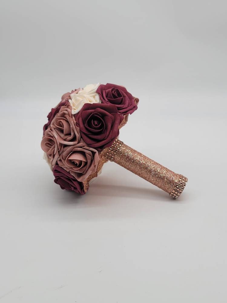 Dusty rose, cream, and burgundy roses. handle is made out of rose gold ribbon and finished with rose gold bling wrap.