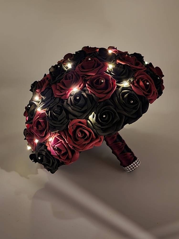 Burgundy and Black Fairy Lites Bridal Bouquet with black and burgundy ribbon in a French twist. Fairy lights are scattered throughout bouquet