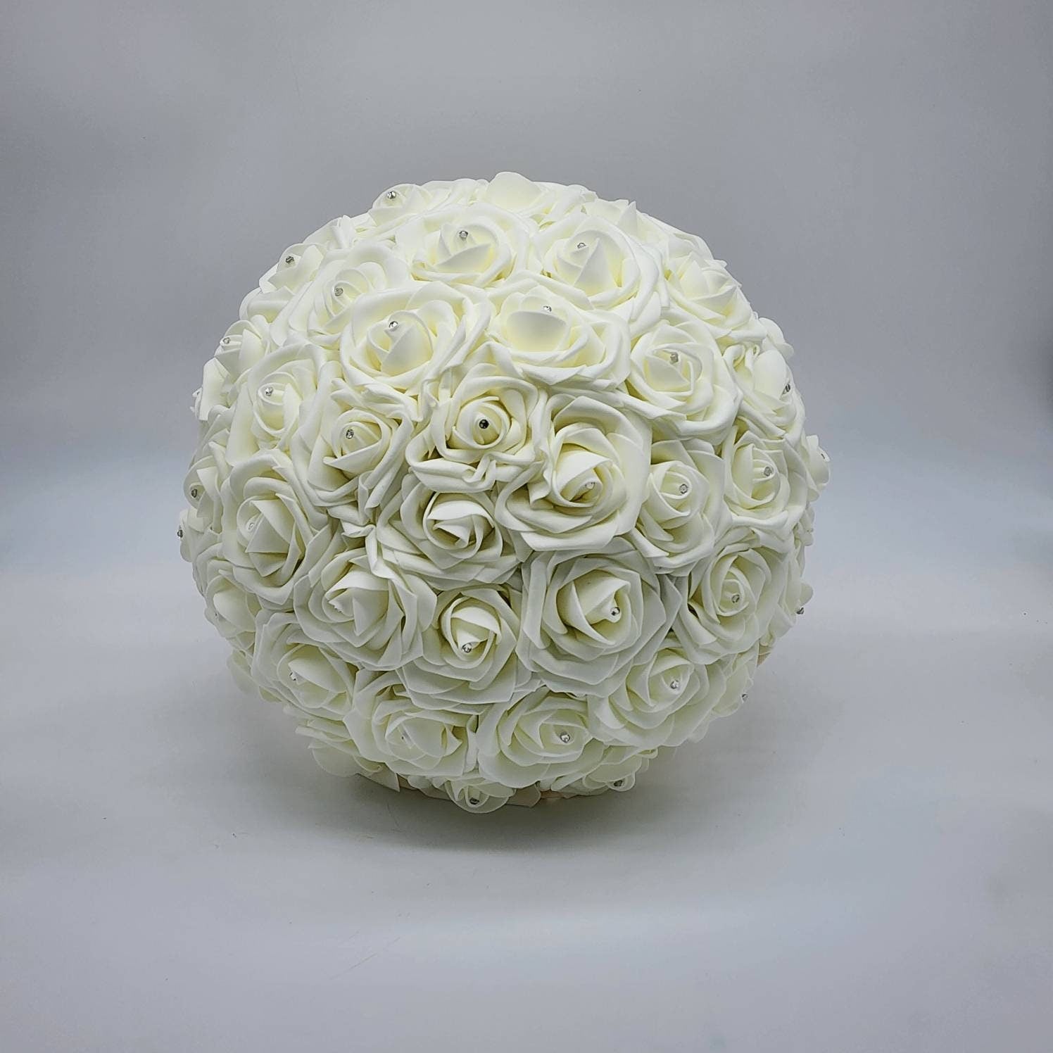 A ivory round bouquet of artificial roses with small rhinestone accents.