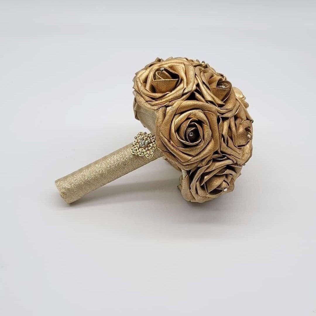 Gold bouquet with rhinestones on every rose. handle is made out of gold ribbon and finished with gold brooch
