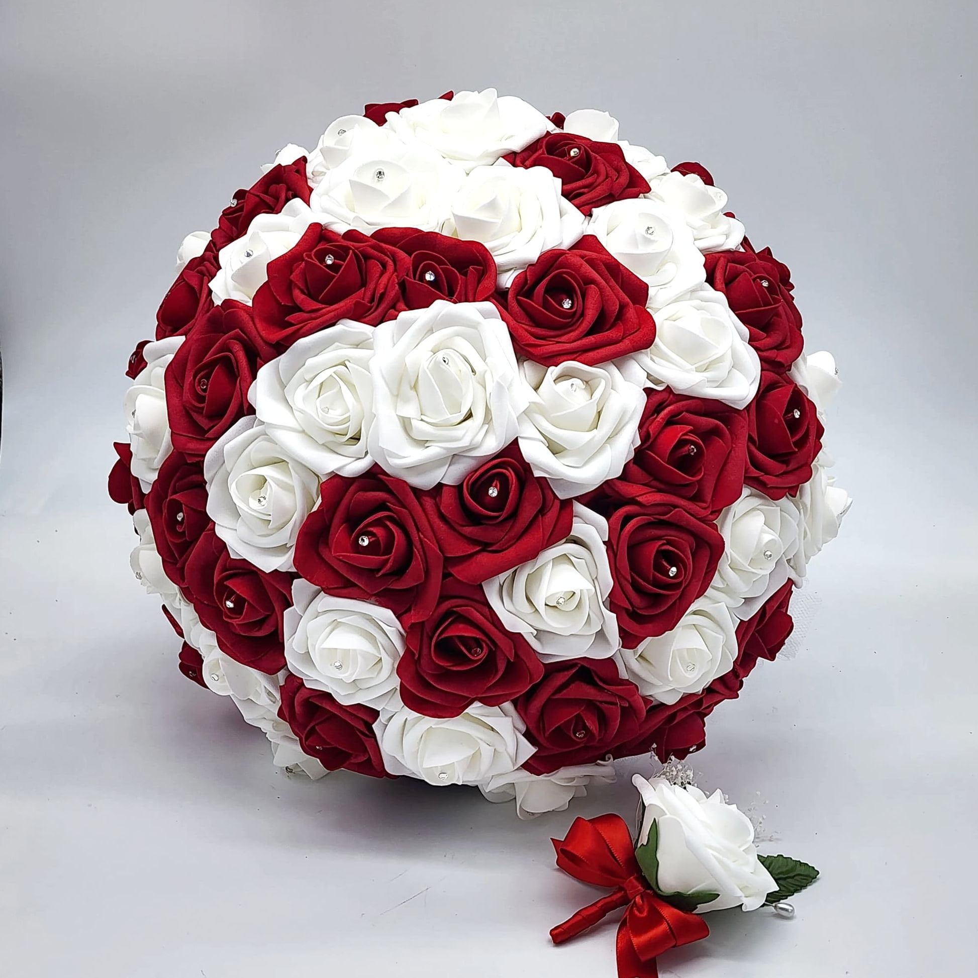 A bridal bouquet made of red and white roses. The bouquet is round and full, with a variety of sizes and shapes of roses.
