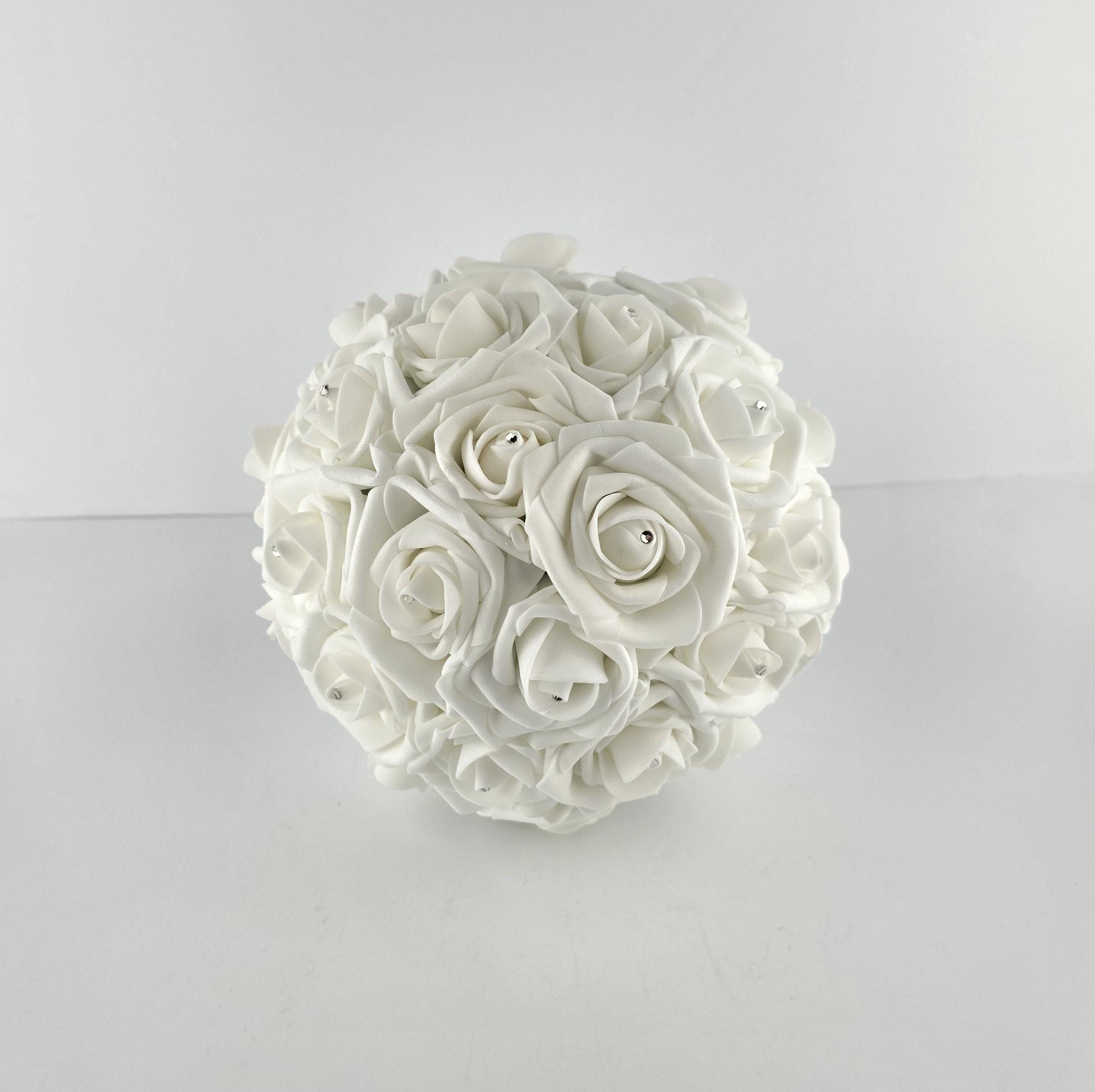 A round bouquet of white roses with silver rhinestone accents. The roses are tightly clustered together, forming a ball shape. The bouquet is set against a plain white background.