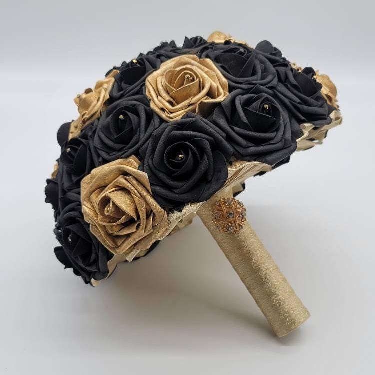 Black and gold bouquet made with real touch roses. Handle is made with gold ribbon. Gold brooch and rhinestones