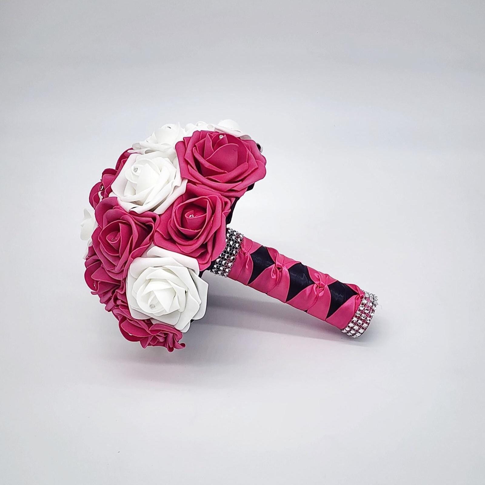 Hot pink and white bouquet with rhinestones on every rose. Handle is made out of hot pink and black satin ribbon and finished with silver bling wrap.