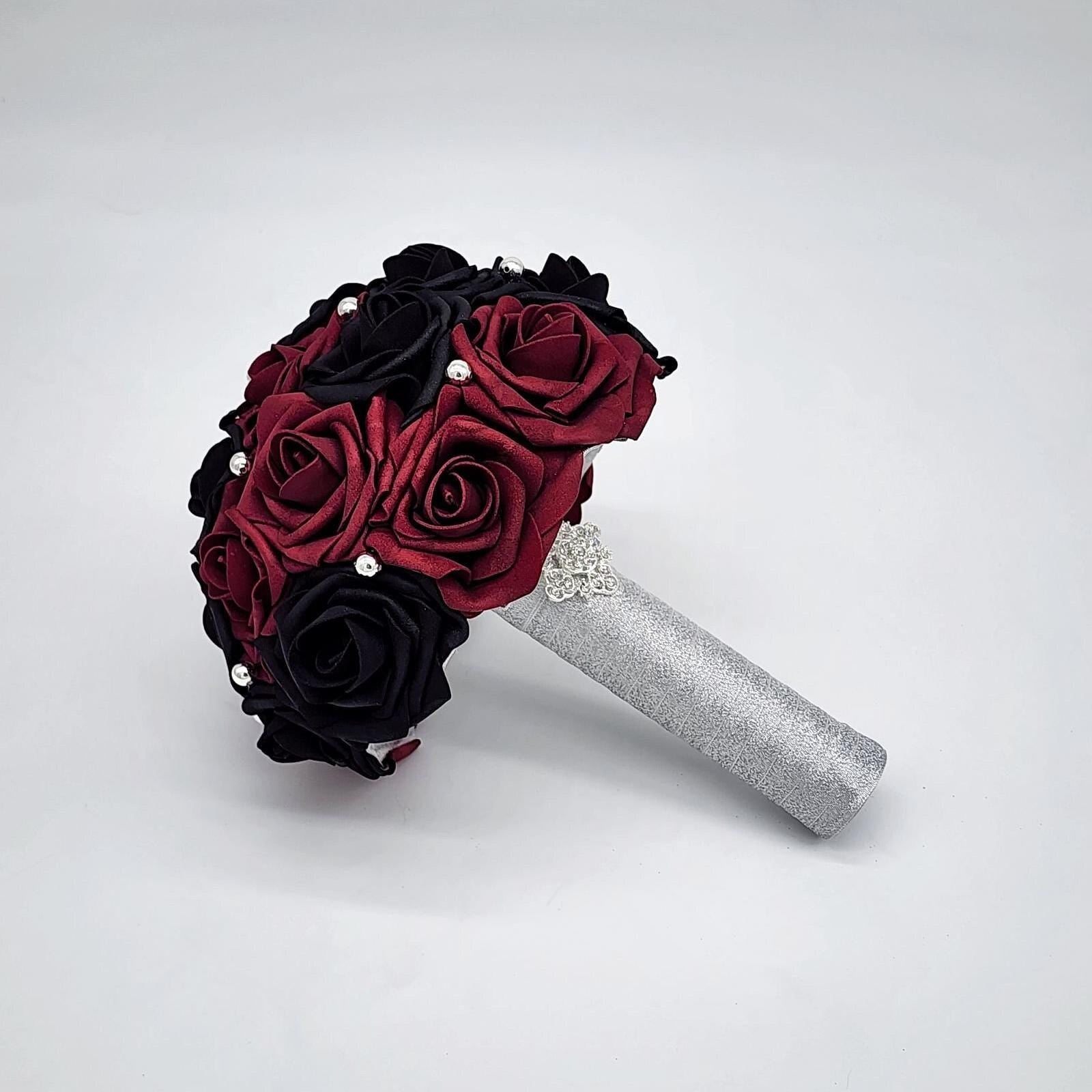 Burgundy and black wedding bouquet made with Real Touch Rose. Silver balls are scattered throughout bouquet. Handle is made with silver ribbon and finished with silver brooch.
