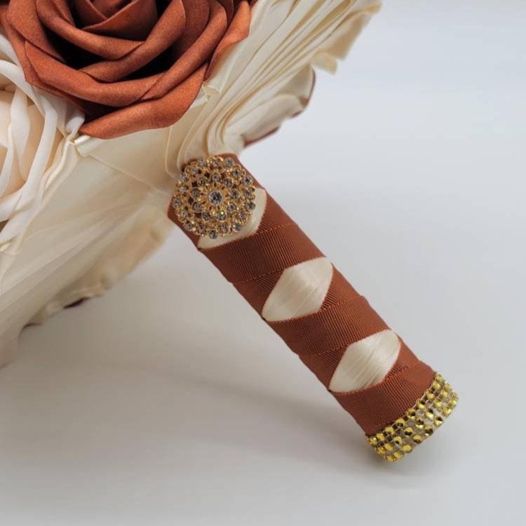 Handle is burnt orange and ivory with gold brooch and bling wrap.