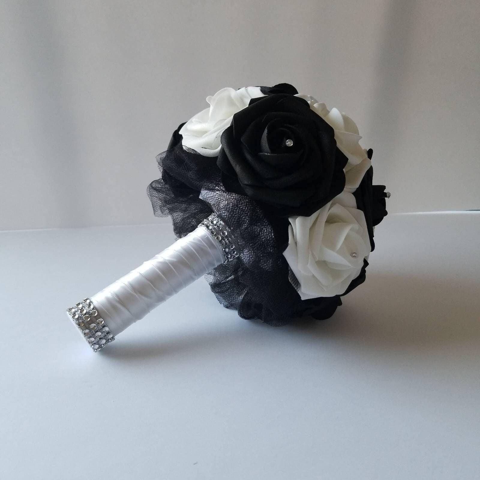 White and black wedding bouquet made with real touch roses. Rhinestones are in the center of every rose. Handle is made with black tulle, white satin ribbon and finished with silver bling wrap.