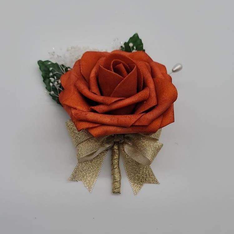 burnt orange and gold boutonniere with baby's breath.