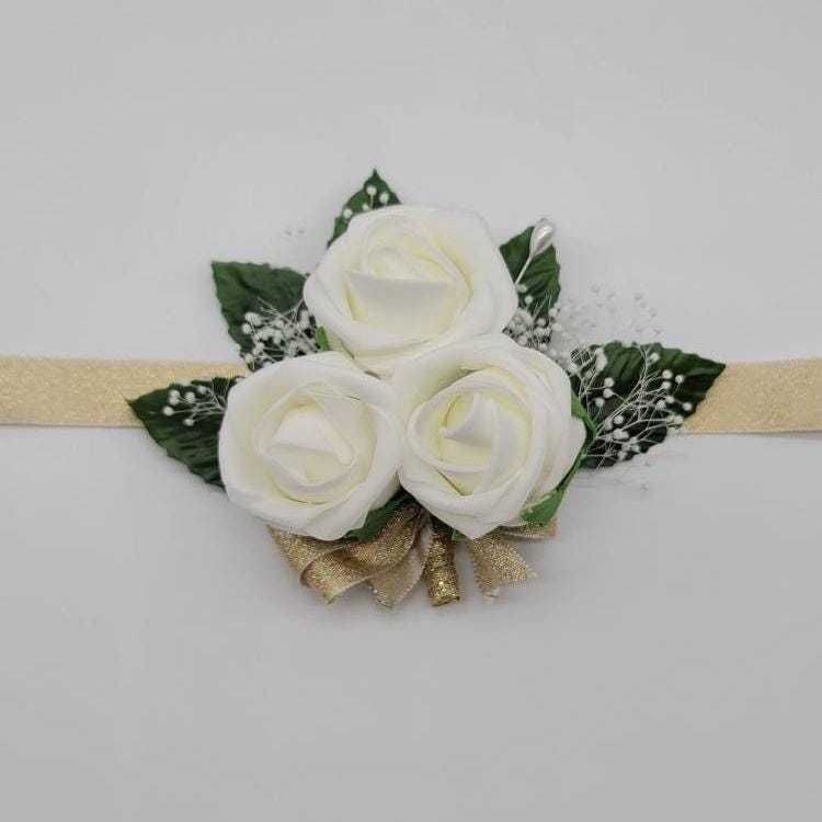 Ivory wrist corsage with gold ribbon and baby's breaths