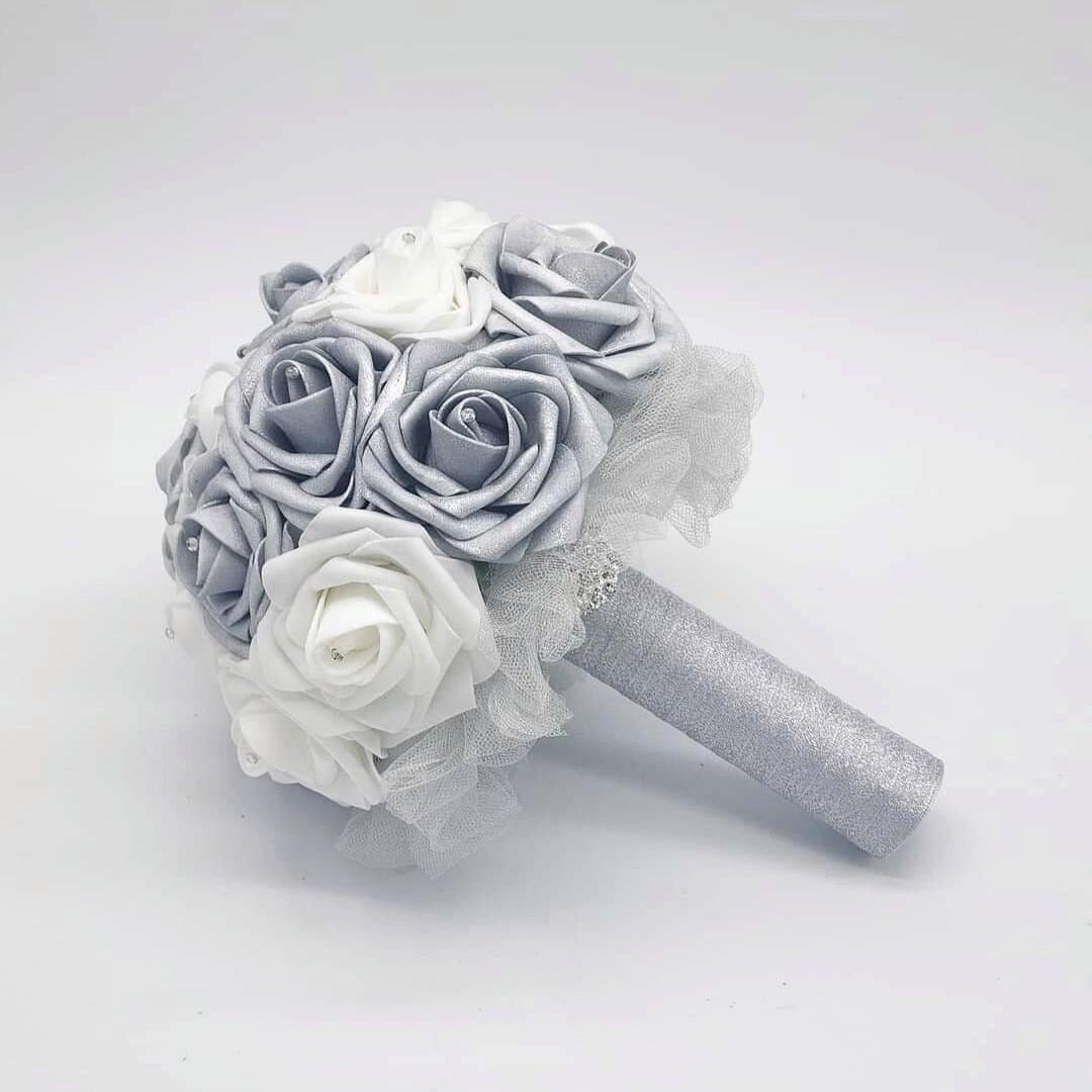 A silver and white bridal bouquet with a silver glitter handle. The bouquet is made of real touch roses and features tulle handle