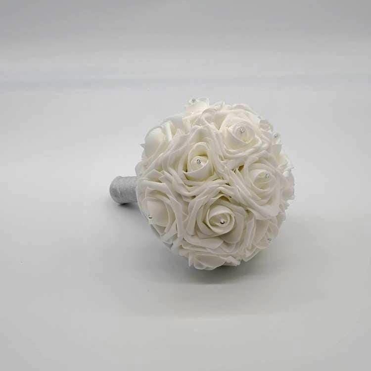 White wedding bouquet made from Real Touch Roses. Rhinestones are placed in the center of every rose. Handle is made up of pvc and finished with silver ribbon.