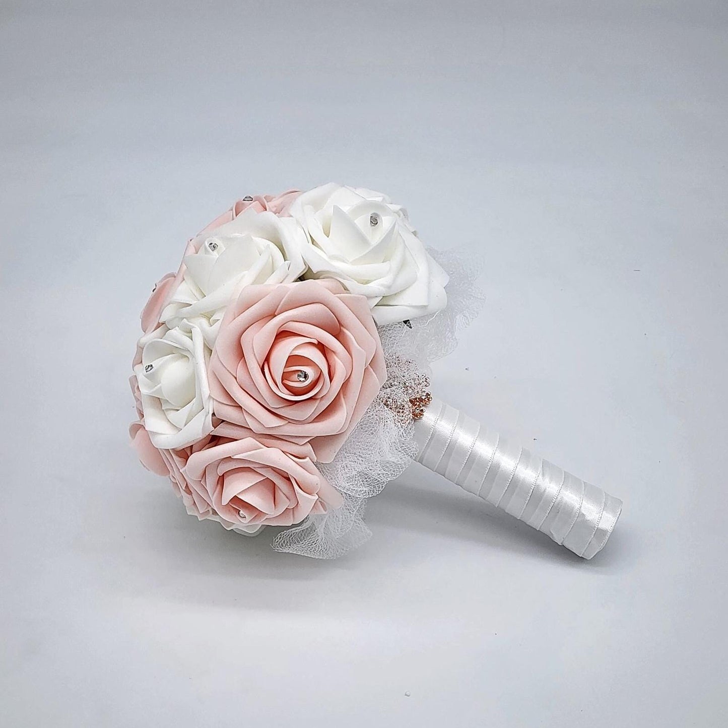 blush and white rose bouquet with rhinestones on every rose. handle is made up of white tulle and ribbon and finished with rose gold brooch,