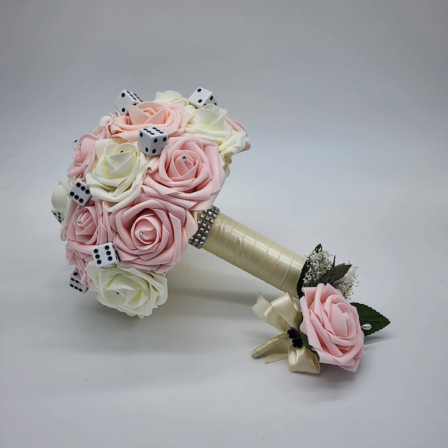 Blush and ivory Las Vegas bouquet with ivory ribbon. Rhinestones and cart suits are scattered throughout roses. Handle is finished with silver bling wrap