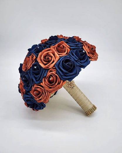 Burnt orange and navy wedding bouquet. Rhinestones on every rose. handle is made up of gold ribbon and finished with gold brooch and bling wrap.