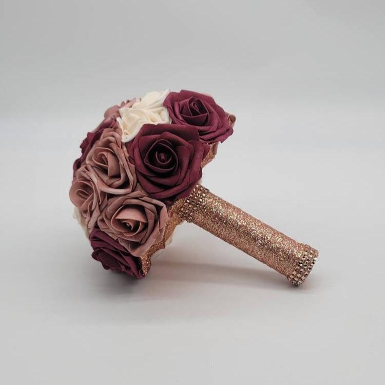 Dusty rose, cream, and burgundy roses. handle is made out of rose gold ribbon and finished with rose gold bling wrap.