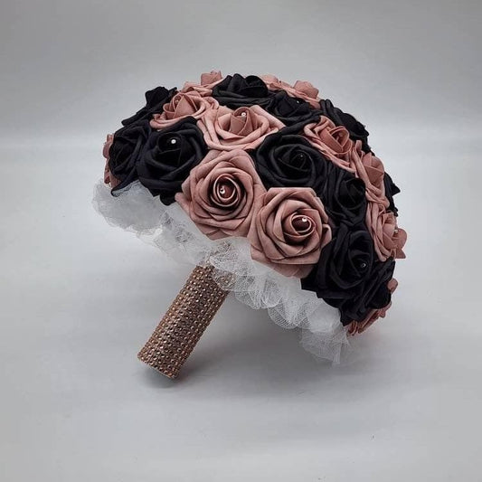 Dusty rose and black roses with rhinestone with every rose. Handle is made out of white tulle and rose gold bling wrapped on the whole handle.