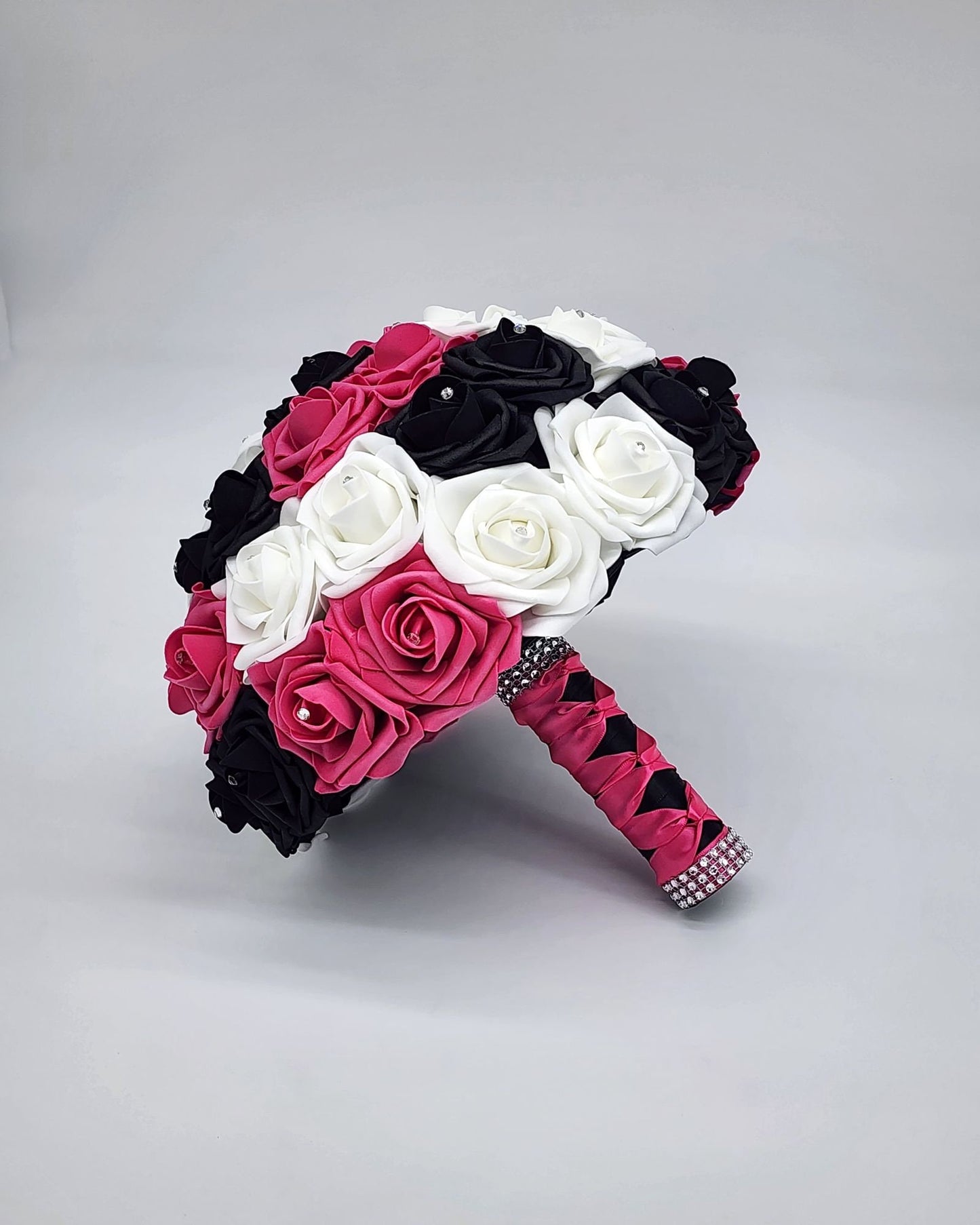 Hot pink, black, and white bouquet with rhinestones on every rose. Handle is made out of hot pink and black satin ribbon in a French twist and ends with silver bling wrap.