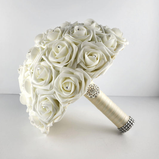 Ivory roses with rhinestones on every rose. Handle is made out of ivory satin ribbon and finished with silver bling wrap.