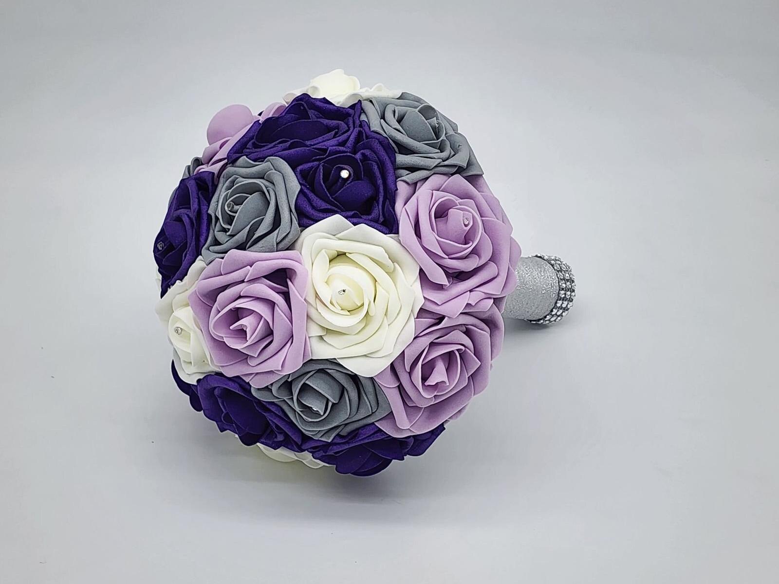 Purple, ivory and gray bridal bouquet with silver handle wrapped in bling wrap. Rhinestones are on every rose.