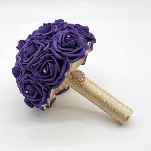 Purple real touch roses bouquet with gold ribbon handle and finished with a gold brooch. rhinestones on every rose.