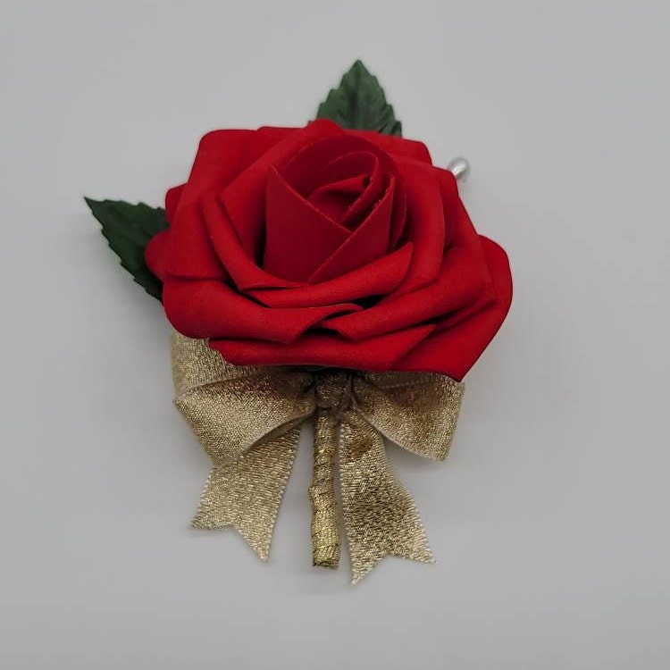 Red rose boutonniere with gold ribbon. 2 green faux leaves. Pearl pin