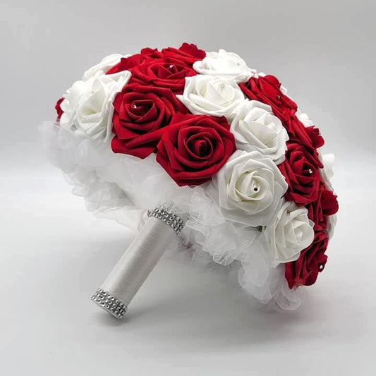 Red and white roses with rhinestones on every rose. Handle is made up of white tulle and white satin ribbon and finished with silver bling wrap.