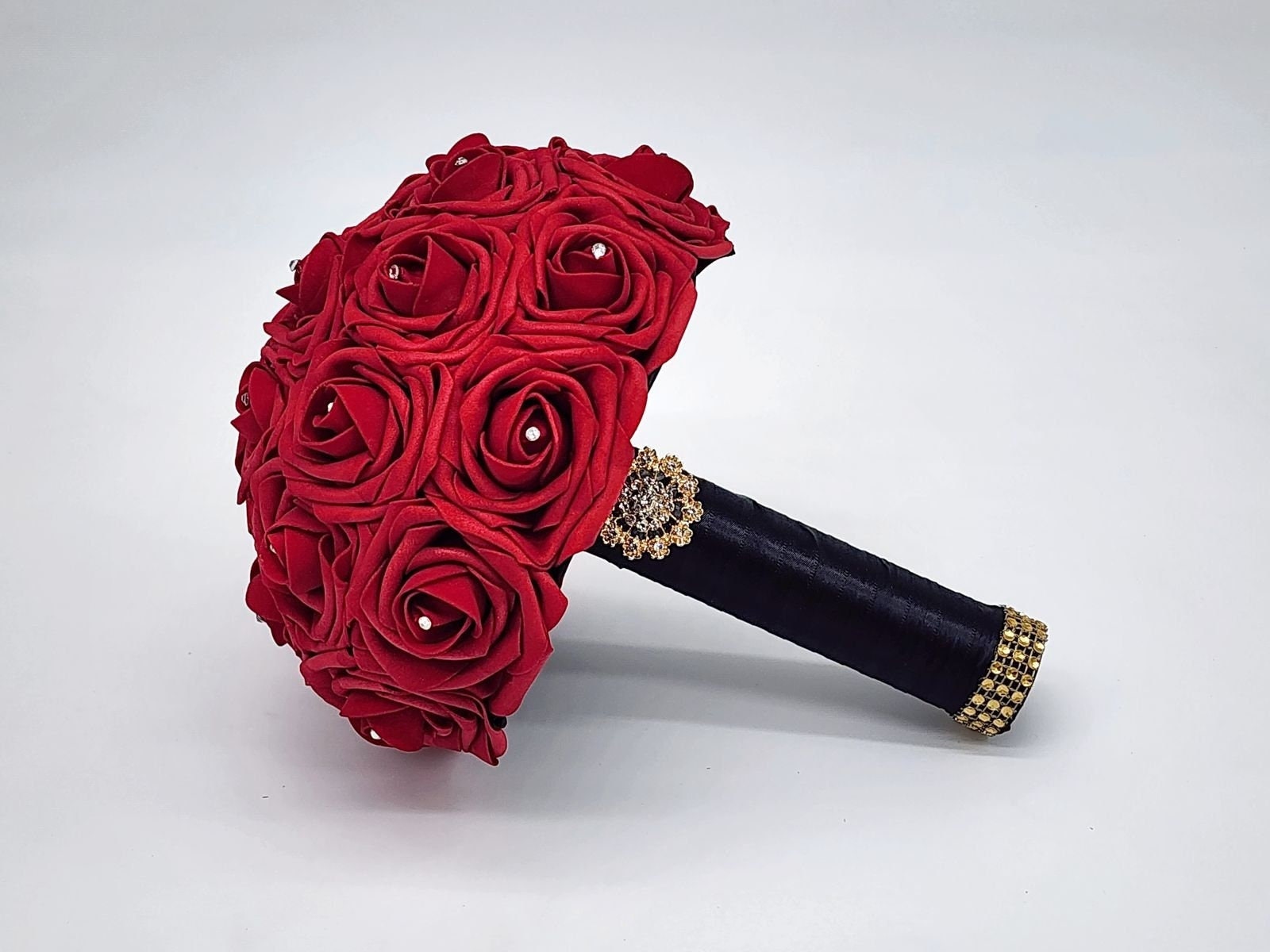 Red Real Touch Roses Wedding Bouquet with Black Satin Ribbon handle. Handle is finished with a gold brooch and gold bling wrap. Rhinestones are on every rose. Great for brides, bridesmaids, prom, homecoming, and Quinceanera.