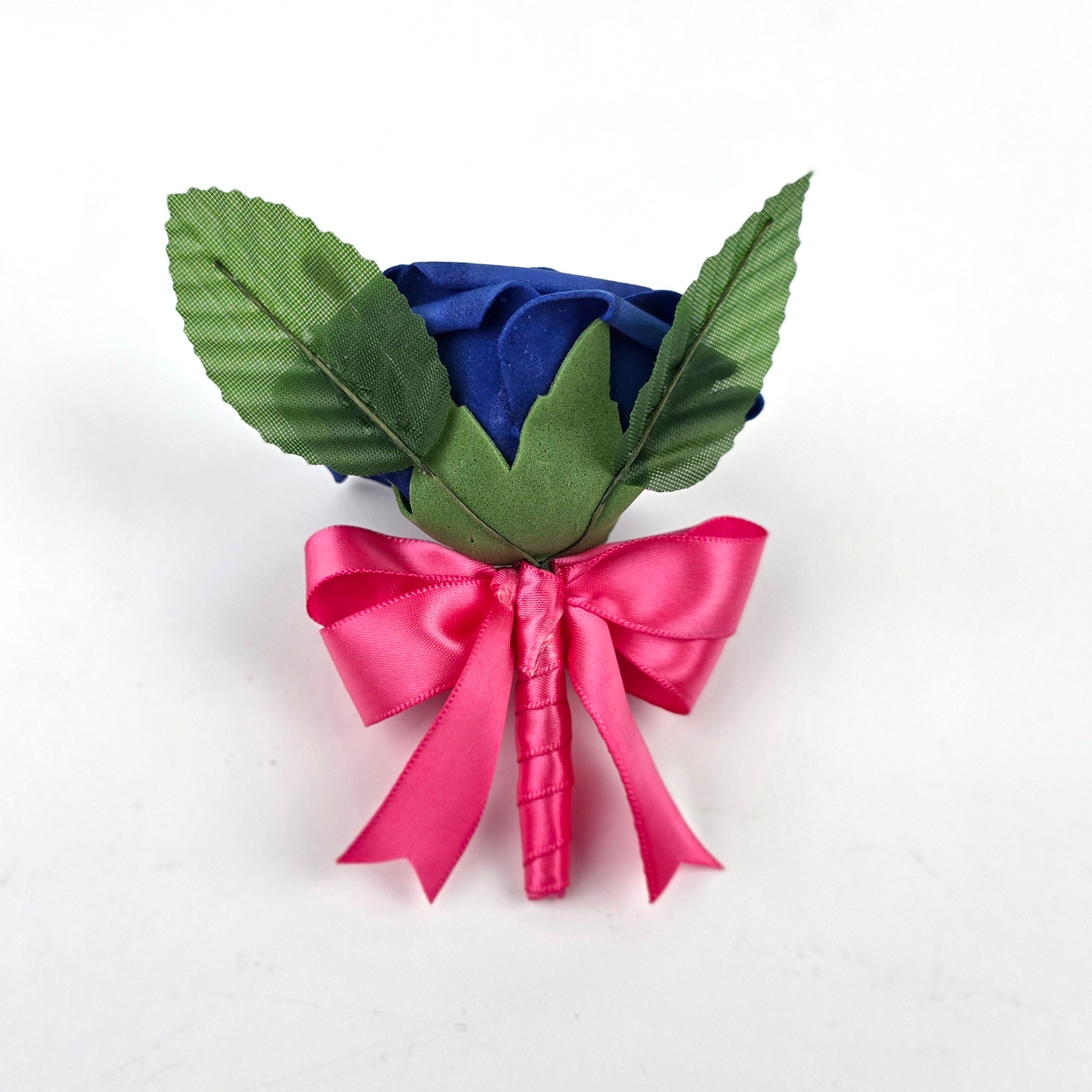 The back of a royal blue boutonniere with hot pink ribbon. 2 green leaves