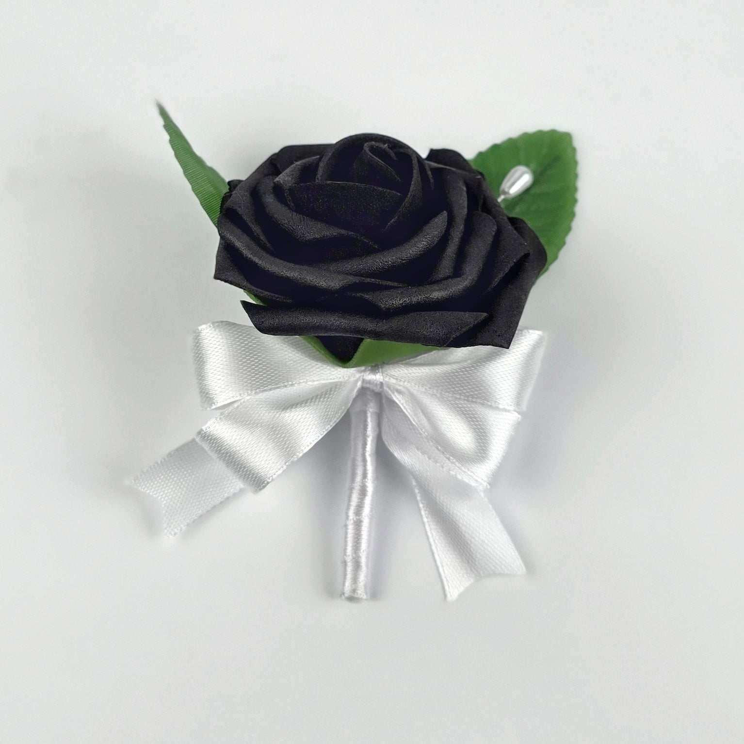 A black rose boutonniere with white satin ribbon