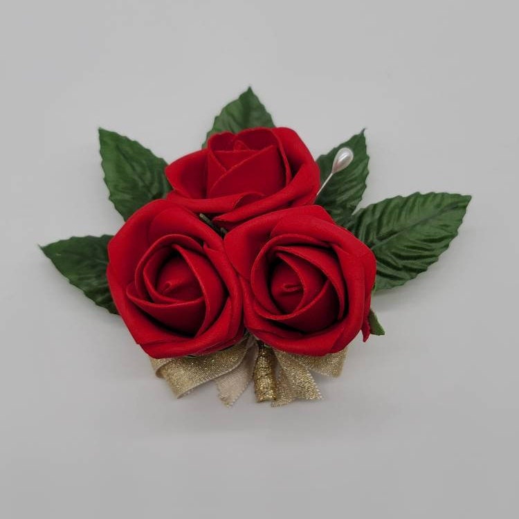 pin on corsage with pearl pin.  3 small rose buds with faux leaves and gold ribbon