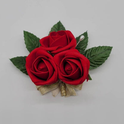 pin on corsage with pearl pin.  3 small rose buds with faux leaves and gold ribbon