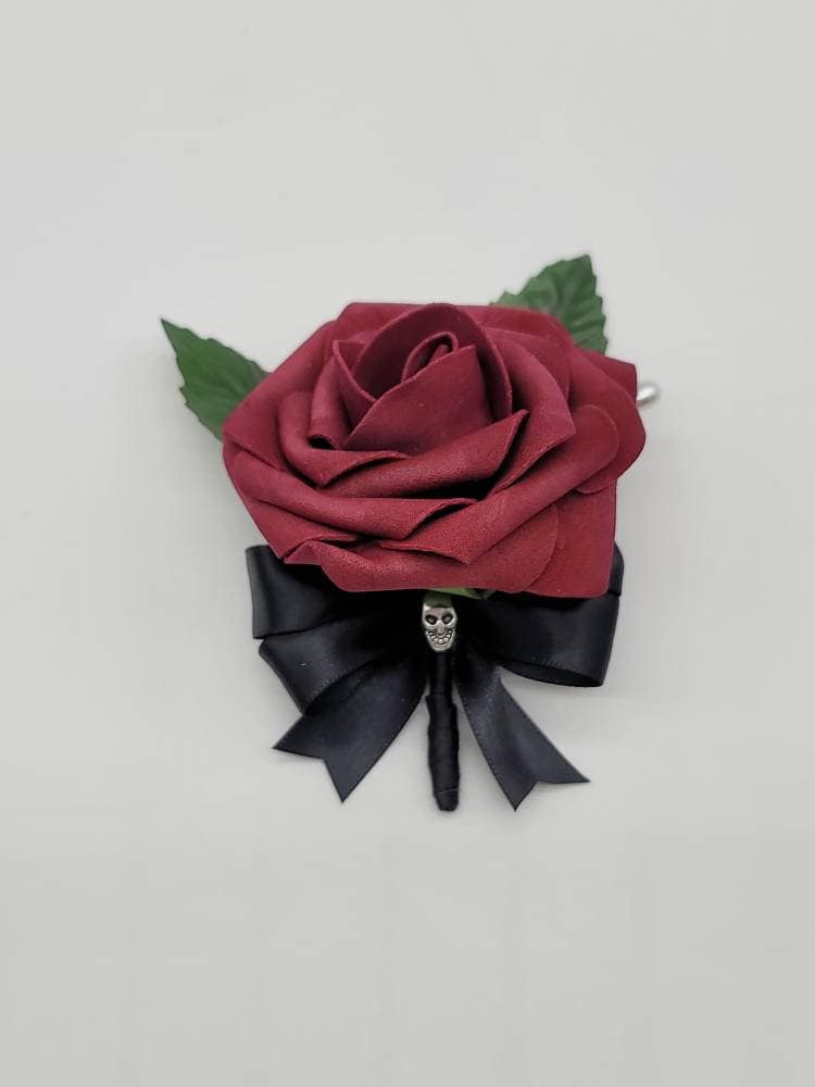 Burgundy real touch roses with black satin ribbon. Silver skull accent with faux leaves and pearl pin