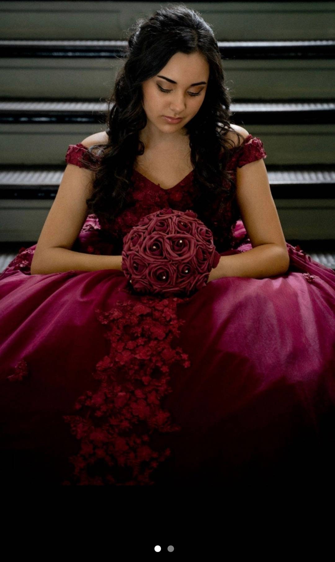 Quinceanera shows girl sitting down holding her bouque.