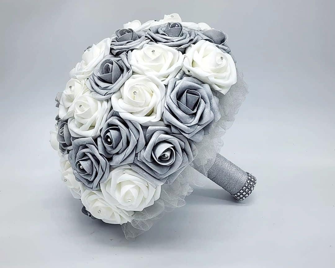 A bridal bouquet made of white and silver Real Touch roses with a silver ribbon and rhinestones.