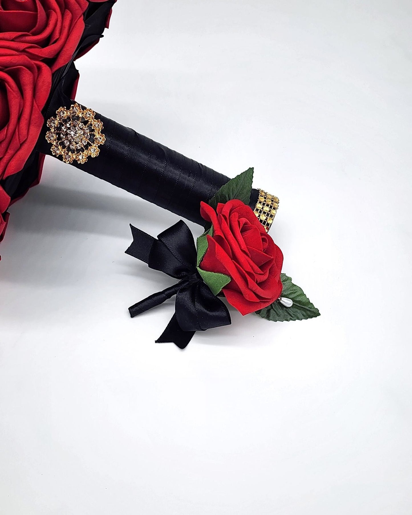 Red rose boutonniere leaning up against handle of bouquet. Rose is read handle is black with a pearl pin.