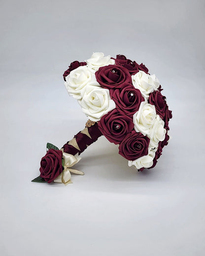 Burgundy and ivory wedding bouquet made with Real Touch Roses. Rhinestones are in the center of Roses. Handles is ivory and burgundy French twist and finished withgold brooch and gold bling wrap