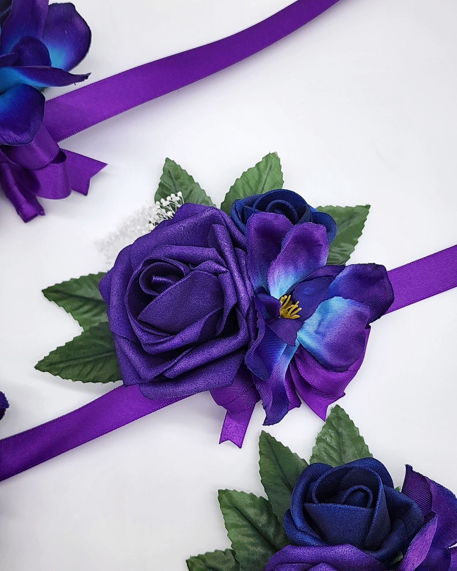 Galaxy wrist corsage with purple and royal blue real touch roses. A galaxy orchid and purple ribbon.