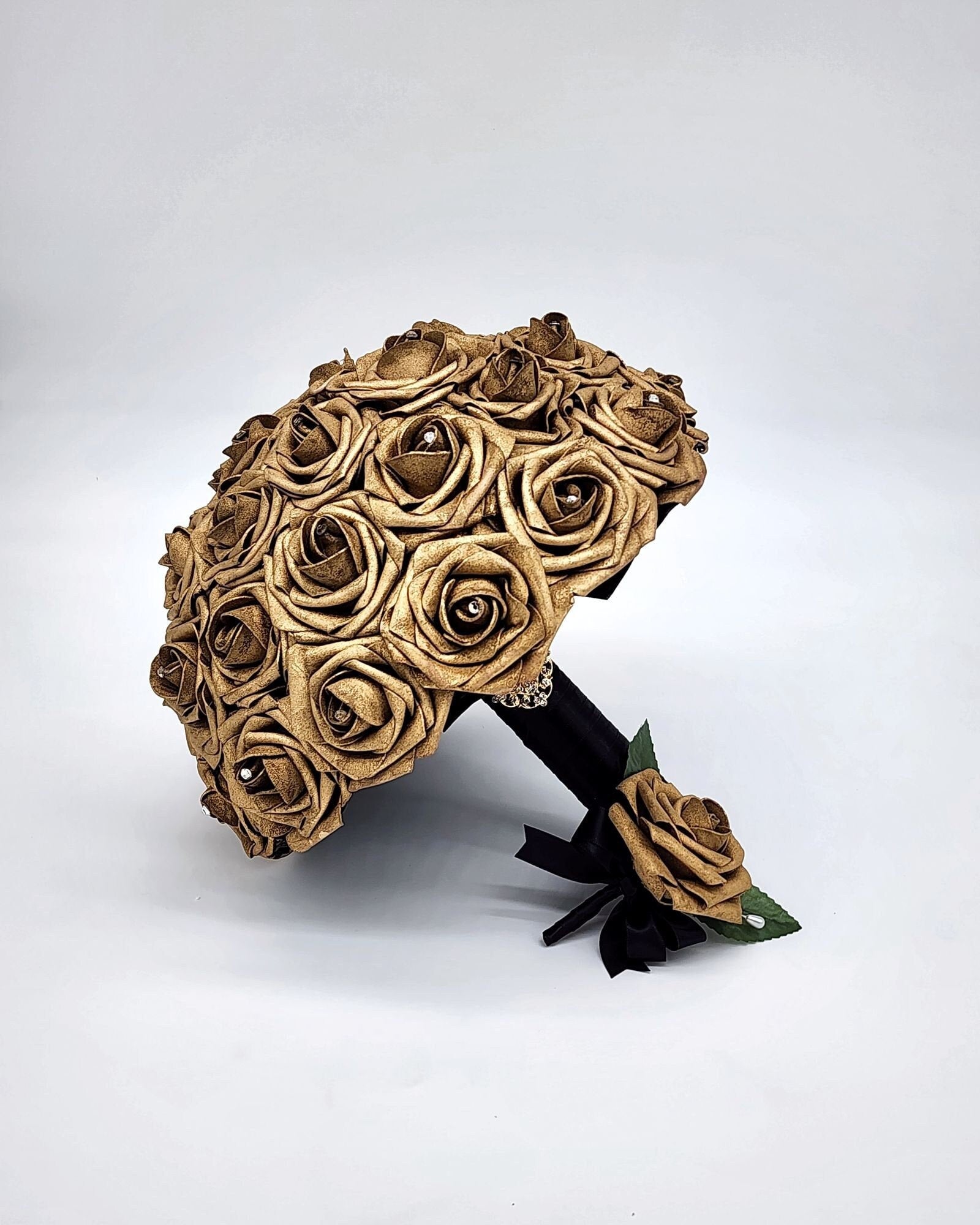 gold roses with rhinestones on every rose. handle is made out of black satin ribbon and finished with a gold brooch.