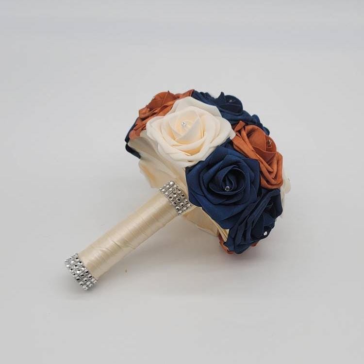 Burnt orange, Navy, and cream wedding bouquet with rhinestones on every rose. Ivory ribbon