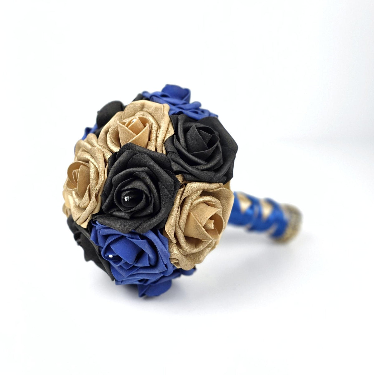 A round bouquet of artificial roses in black, metallic gold, and royal blue. The flowers are arranged in a dense, spherical cluster. The handle of the bouquet is wrapped in a matching royal blue ribbon with gold accents.