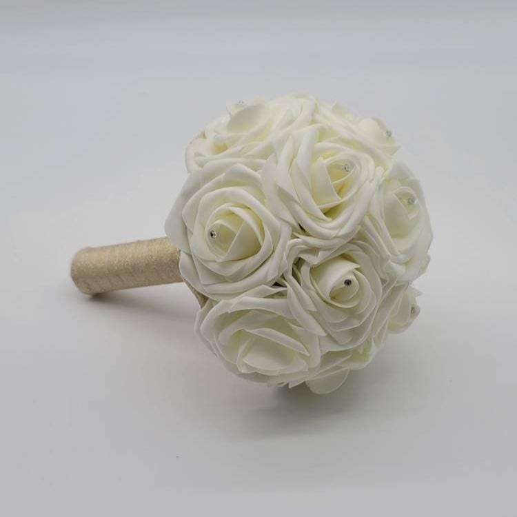 A Ivory wedding bouquet made with Real Touch Roses. Rhinestones on every rose. Glittery gold handle.