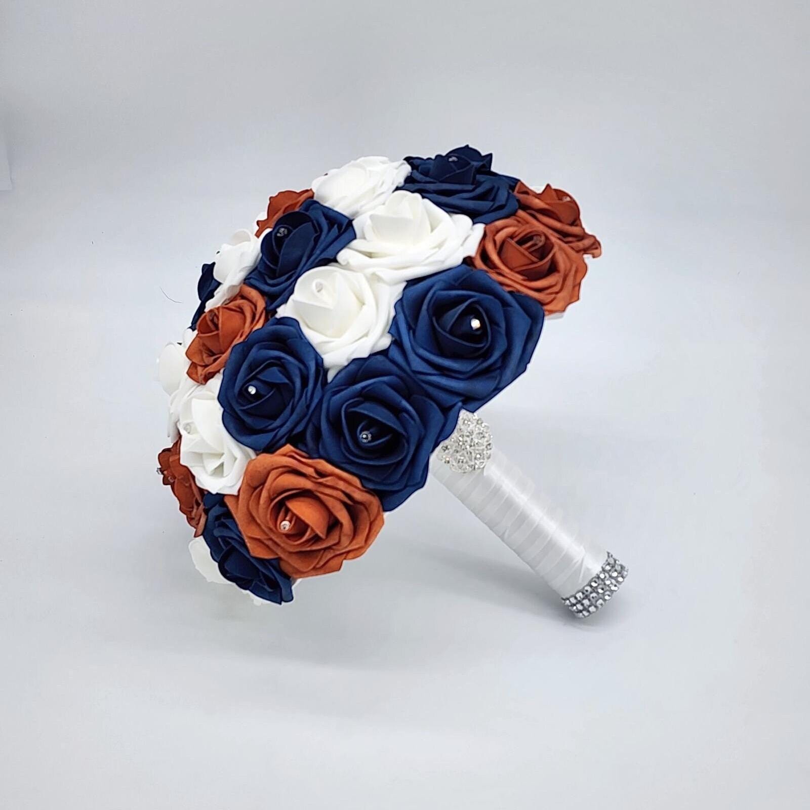 burnt orange, navy, and white bouquet with rhinestones on every rose. handle is made up of white satin ribbon and finished with silver brooch and bling wrap.