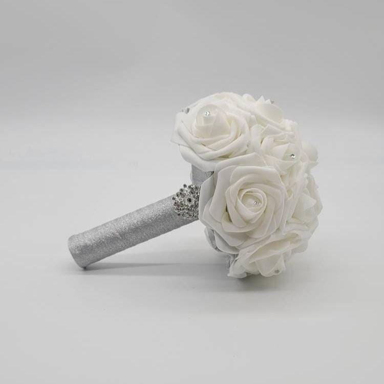 White bridal bouquet with white real touch roses and silver ribbon handle.