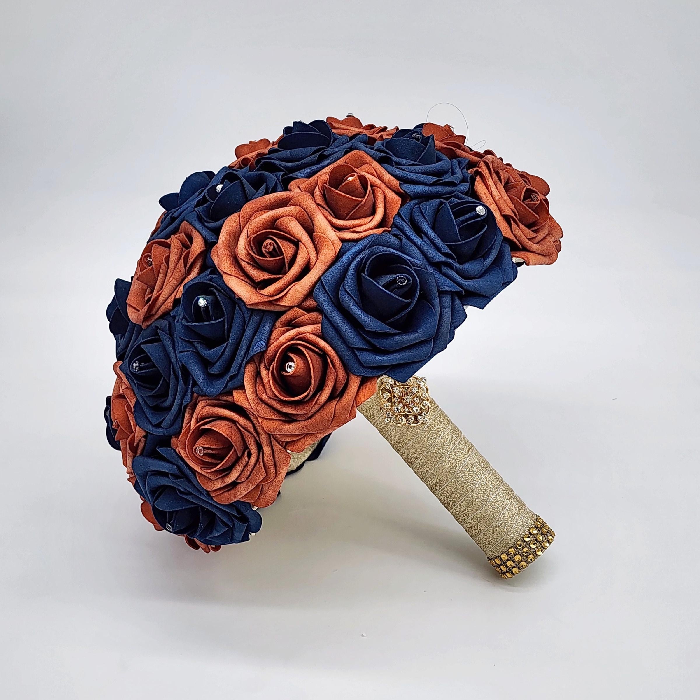 Burnt orange and navy wedding bouquet. Rhinestones on every rose. handle is made up of gold ribbon and finished with gold brooch and bling wrap.