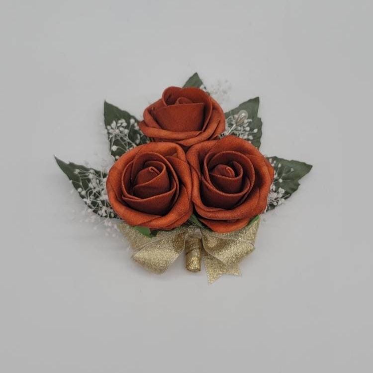 burnt orange pin on corsage with gold ribbon and baby's breath