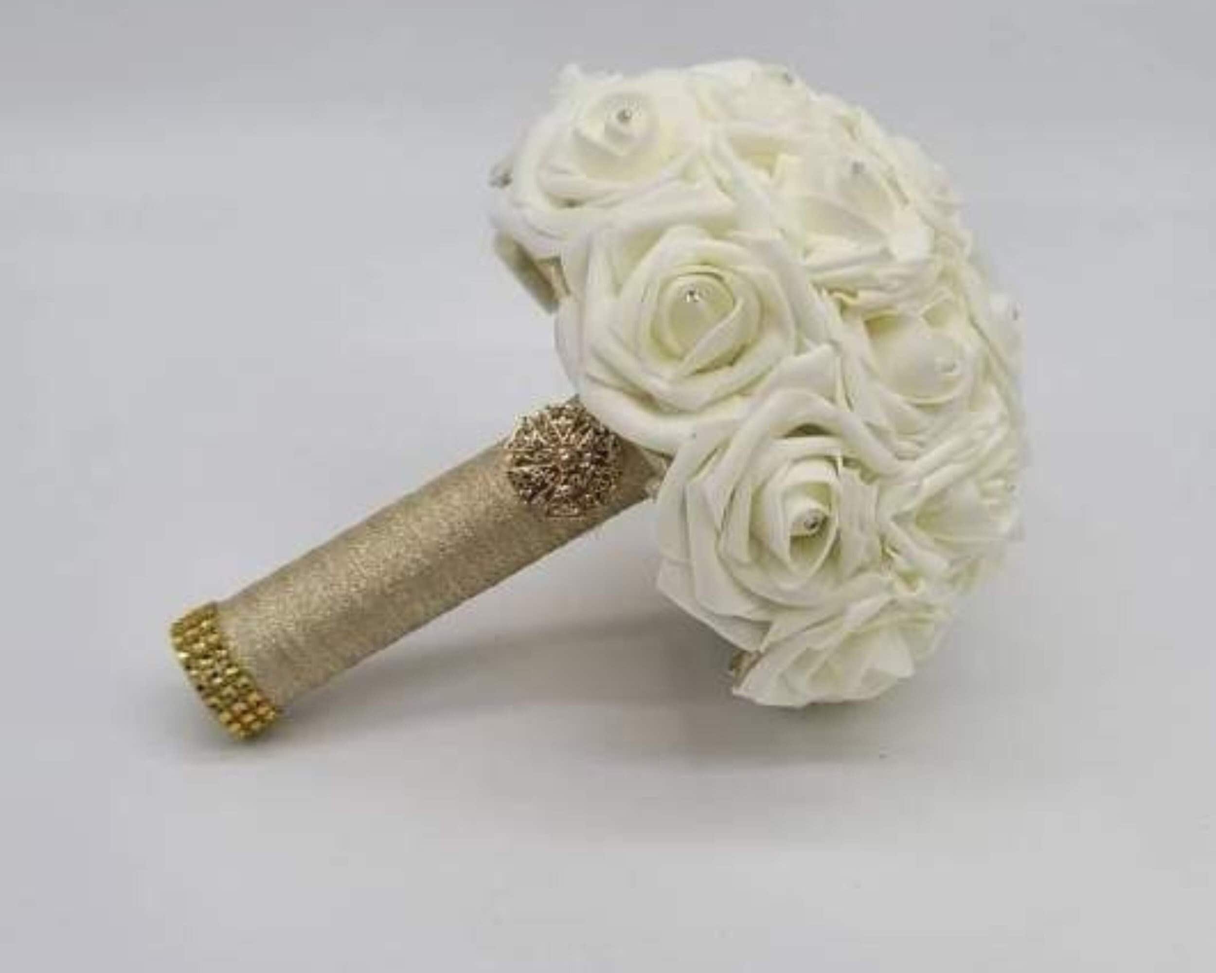 Ivory real touch roses bouquet with gold handle finished with gold brooch and bling wrap. Each flower has rhinestones in the center.