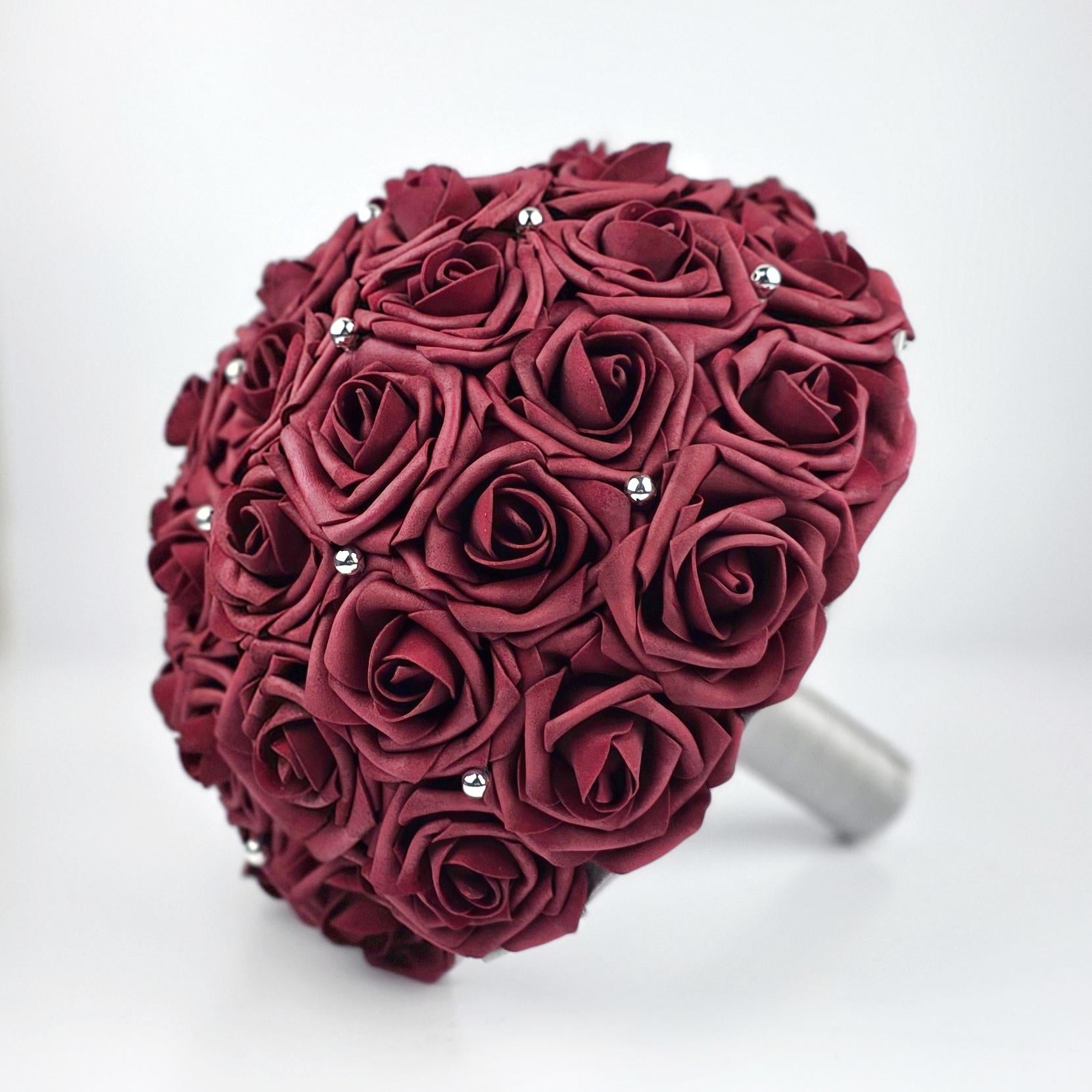 Burgundy real touch rose bouquet with silver ribbon. Silver balls are scattered throughout bouquet