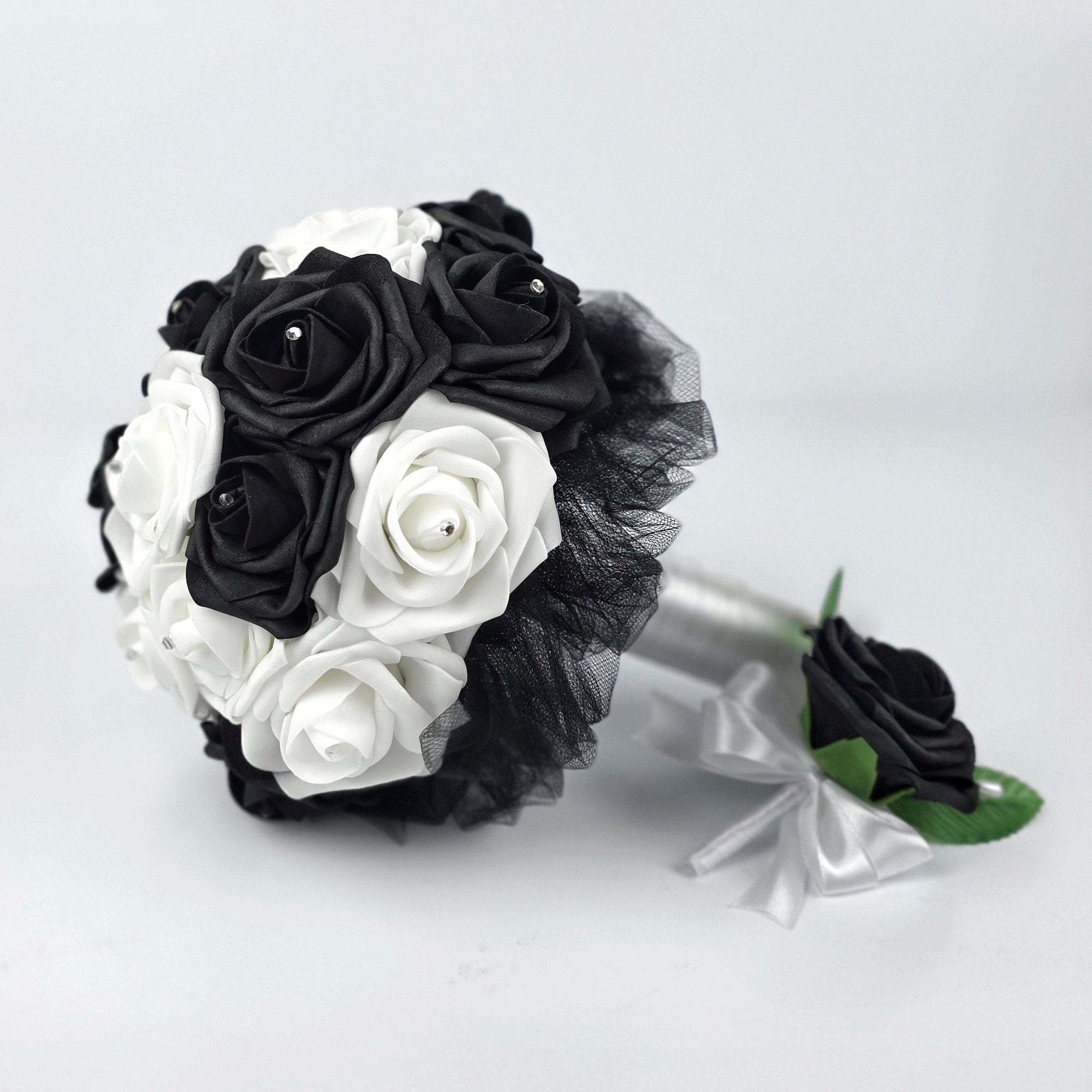 Black boutonniere with white ribbon with matching bouquet with white and black roses, black tulle, and white satin ribbon.